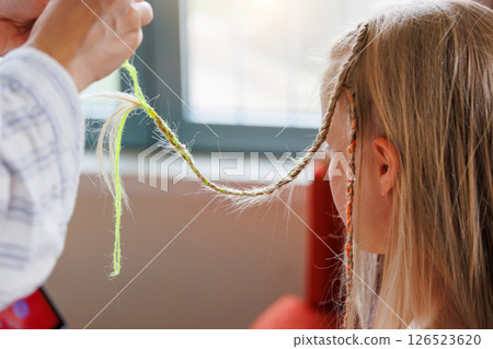 Mom hands making colorful braided hair cute blonde girl sunny day seaside beach coast vacation. She stands balcony seaside resort joyful holiday vibe. Carefree little child stylish summer hairstyle Mom hands making colorful braided hair cute blonde girl sunny day seaside beach coast vacation. She stands balcony seaside resort joyful holiday vibe. Carefree little child stylish summer hairstyle 126523620