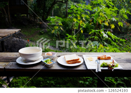 Fresh hot dog and fried egg with boiled rice and buttered toast in white bowl on wooden table for breakfast in the morning in garden of tropical resort in Thailand Fresh hot dog and fried egg with boiled rice and buttered toast in white bowl on wooden table for breakfast in the morning in garden of tropical resort in Thailand 126524193