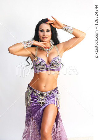 Beautiful Eastern Dance Performer in a Flowing Purple Dress Against a White Background 126524244