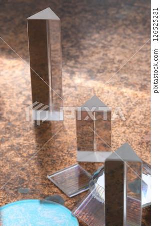 Three triangular glass objects are on a brown surface 126525281