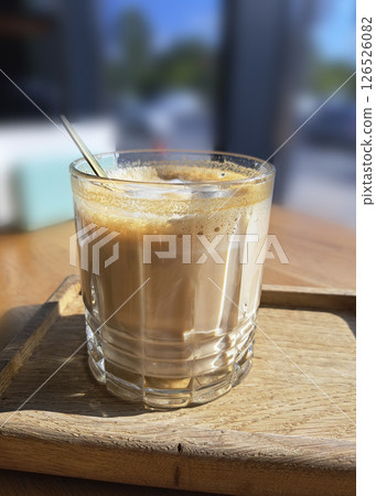 Aromatic cappuccino in a glass on a wooden stand in the interior of a cafe. 126526082