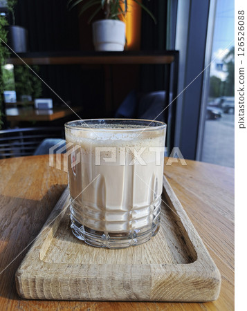 Aromatic cappuccino in a glass on a wooden stand in the interior of a cafe. Aromatic cappuccino in a glass on a wooden stand in the interior of a cafe. 126526088