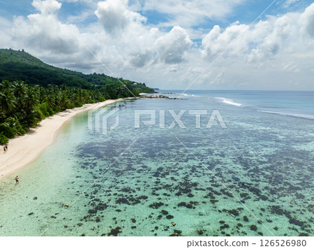 Serene sandy shore and calm azure water with a coral reef. Anse Marie Louise, Seychelles, Mahe. 126526980