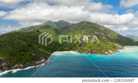 Secluded beach surrounded by lush green hills and turquoise water. Seychelles, Mahe. Anse Du Riz beach. Baie Ternay Marine National Park. 126526987