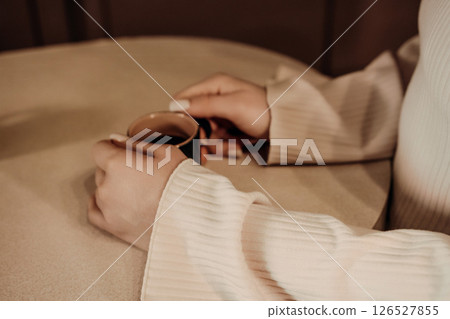 Hands Coffee Cup Cozy Interior: Woman enjoying coffee indoors, close-up. Hands Coffee Cup Cozy Interior: Woman enjoying coffee indoors, close-up. 126527855