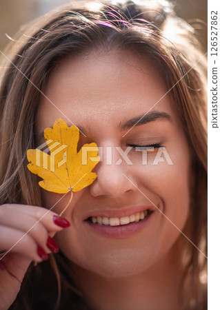 Woman Leaf Autumn Outdoors: Portrait Smiling Girl Holds Yellow Leaf Covering Eye, Fall Season. Woman Leaf Autumn Outdoors: Portrait Smiling Girl Holds Yellow Leaf Covering Eye, Fall Season. 126527862