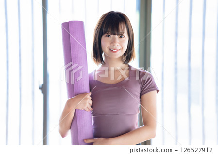 Young woman with a yoga mat 126527912