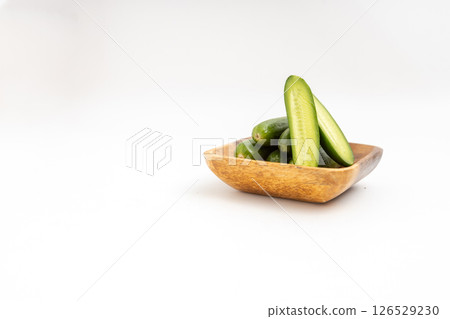 小木盤上的迷你黃瓜。白色背景上小黃瓜的庫存照片 小木盤上的迷你黃瓜。白色背景上小黃瓜的庫存照片 126529230