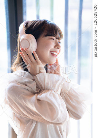 Close-up of a young woman listening to music through headphones Close-up of a young woman listening to music through headphones 126529420