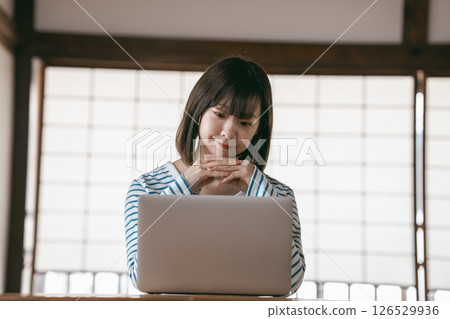 A young woman using a laptop in a Japanese-style room 126529936