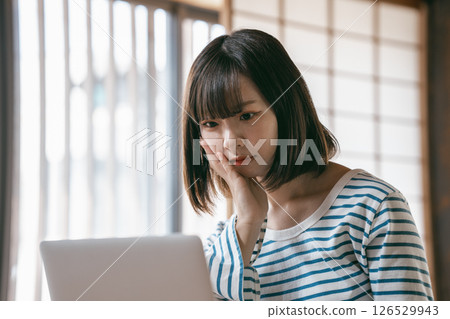 A young woman using a laptop in a Japanese-style room 126529943