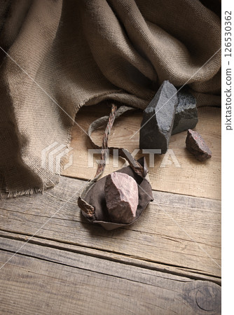 An antique leather sling lies on wooden desk An antique leather sling lies on wooden desk 126530362