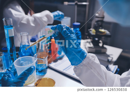 Scientist pipetting medical samples into microplate in laboratory 126530838