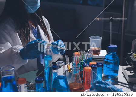 Scientist pipetting medical samples into microplate in laboratory 126530850