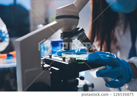 Scientist pipetting medical samples into microplate in laboratory 126530875