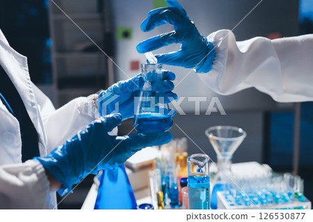 Scientist pipetting medical samples into microplate in laboratory 126530877
