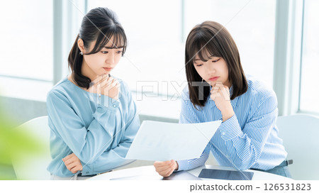 兩位女士/女商人一邊看文件一邊思考 兩位女士/女商人一邊看文件一邊思考 126531823