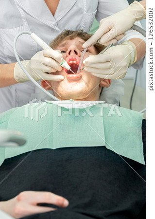 Dental procedure during an examination with a young patient in a modern clinic setting Dental procedure during an examination with a young patient in a modern clinic setting 126532002
