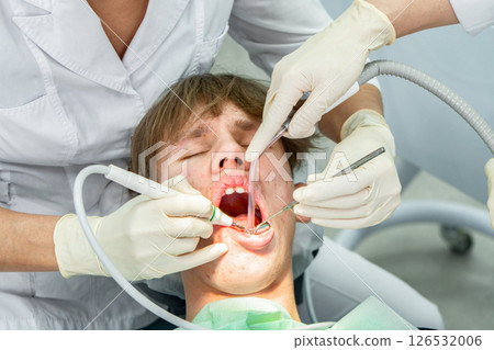 Dental procedure during an examination with a young patient in a modern clinic setting Dental procedure during an examination with a young patient in a modern clinic setting 126532006