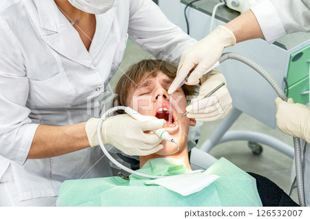 Teenager receiving dental treatment in modern clinic during daytime Teenager receiving dental treatment in modern clinic during daytime 126532007