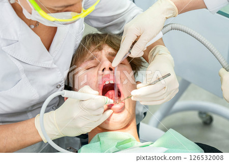 Dental procedure during an examination with a young patient in a modern clinic setting Dental procedure during an examination with a young patient in a modern clinic setting 126532008
