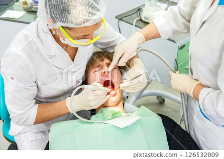 Teenager receiving dental treatment in modern clinic during daytime Teenager receiving dental treatment in modern clinic during daytime 126532009