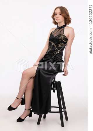 An Elegant and Stylish Model in a Stunning Black Dress Posing Gracefully on a Stool An Elegant and Stylish Model in a Stunning Black Dress Posing Gracefully on a Stool 126532272