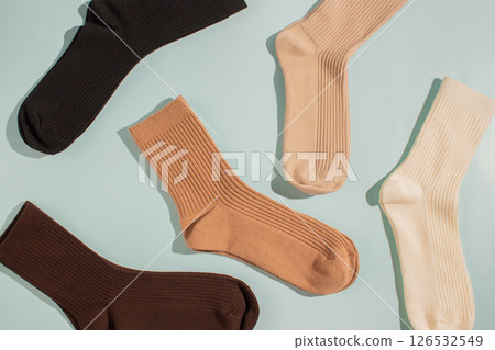 Assorted socks in various colors including brown, beige, and cream, arranged artistically on soft blue background, showcasing texture and style for fashion and apparel marketing Assorted socks in various colors including brown, beige, and cream, arranged artistically on soft blue background, showcasing texture and style for fashion and apparel marketing 126532549
