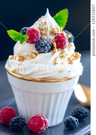 Luxurious whipped cream dessert served in an elegant white ramekin with gold rim. The dessert is topped with fresh raspberries, blackberries, mint leaves, and decorative gold sprinkles. Luxurious whipped cream dessert served in an elegant white ramekin with gold rim. The dessert is topped with fresh raspberries, blackberries, mint leaves, and decorative gold sprinkles. 126532607
