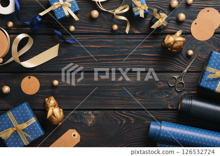 A frame made from gift wrapping supplies. Wrapping paper, tags, and ribbon in blue and gold colors. Place for your text. A frame made from gift wrapping supplies. Wrapping paper, tags, and ribbon in blue and gold colors. Place for your text. 126532724