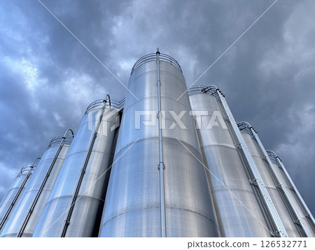 Large stack of silvery tanks with a cloudy sky in the background 126532771