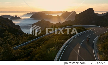 Epic Sunset View in High Mountain Landscape with Motorcycle Driver Riding on Asphalt Road . Pico do Arieiro , Madeira Island . Clouds in the Valley . 126532774