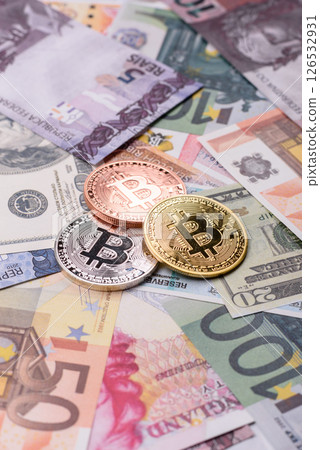 Round metal bitcoin on a background of paper banknotes of different currencies Round metal bitcoin on a background of paper banknotes of different currencies 126532931