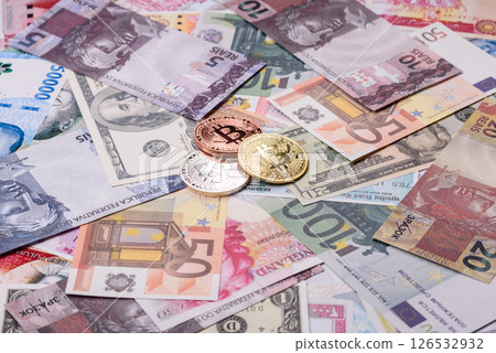 Round metal bitcoin on a background of paper banknotes of different currencies Round metal bitcoin on a background of paper banknotes of different currencies 126532932
