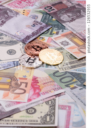 Round metal bitcoin on a background of paper banknotes of different currencies Round metal bitcoin on a background of paper banknotes of different currencies 126532935