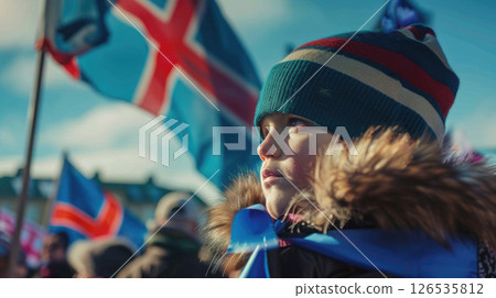 A young Icelandic boy stands among waving Icelandic flags, Iceland Independence Day celebrations, street parade, folk march 126535812