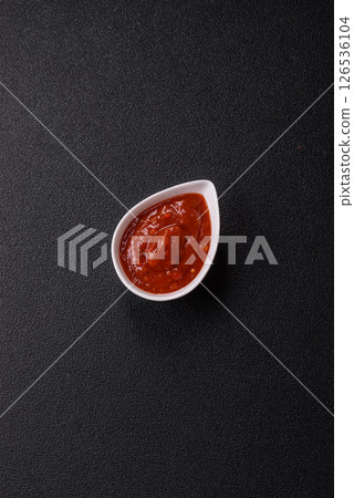 Red sauce or ketchup with salt and spices in ceramic sauce boat 126536104