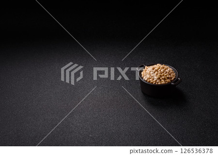 Peeled pine nuts in a bowl on a dark concrete background 126536378