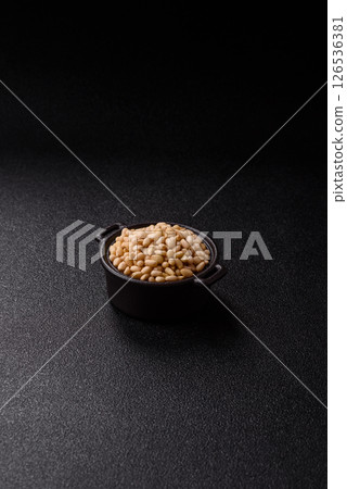 Peeled pine nuts in a bowl on a dark concrete background Peeled pine nuts in a bowl on a dark concrete background 126536381