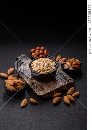 Peeled pine nuts in a bowl on a dark concrete background Peeled pine nuts in a bowl on a dark concrete background 126536393