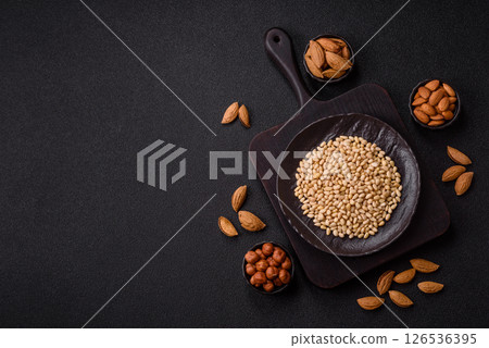 Peeled pine nuts in a bowl on a dark concrete background 126536395