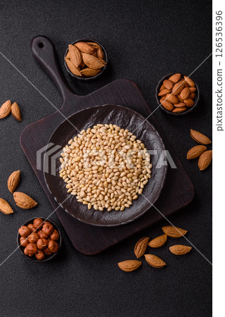 Peeled pine nuts in a bowl on a dark concrete background 126536396
