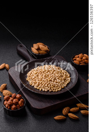 Peeled pine nuts in a bowl on a dark concrete background 126536397