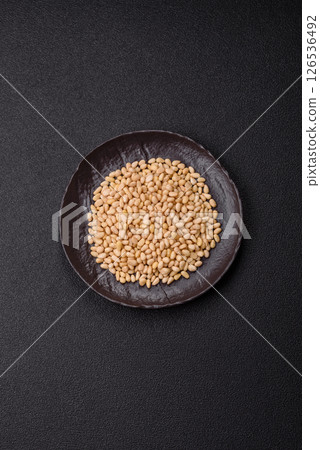 Peeled pine nuts in a bowl on a dark concrete background 126536492