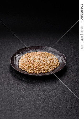 Peeled pine nuts in a bowl on a dark concrete background Peeled pine nuts in a bowl on a dark concrete background 126536493