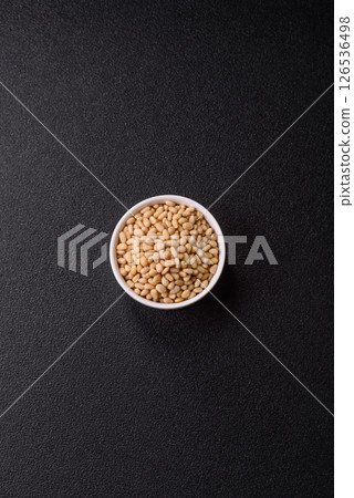 Peeled pine nuts in a bowl on a dark concrete background Peeled pine nuts in a bowl on a dark concrete background 126536498