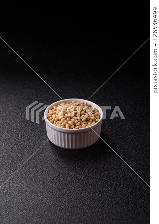 Peeled pine nuts in a bowl on a dark concrete background Peeled pine nuts in a bowl on a dark concrete background 126536499
