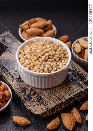 Peeled pine nuts in a bowl on a dark concrete background Peeled pine nuts in a bowl on a dark concrete background 126536507