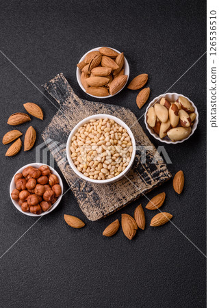 Peeled pine nuts in a bowl on a dark concrete background Peeled pine nuts in a bowl on a dark concrete background 126536510