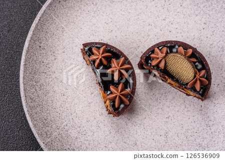 Sweet round tart with chocolate coating and nut filling 126536909